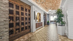 Un pasillo con una bodega de vinos, una recepción y una planta grande en maceta.