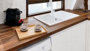 A modern kitchen with a large window, white cabinetry, and a wooden countertop. - 1595 Chapon (Paris)