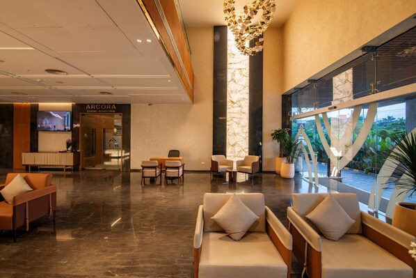A modern lobby with seating areas, a reception desk, and a view through large windows.