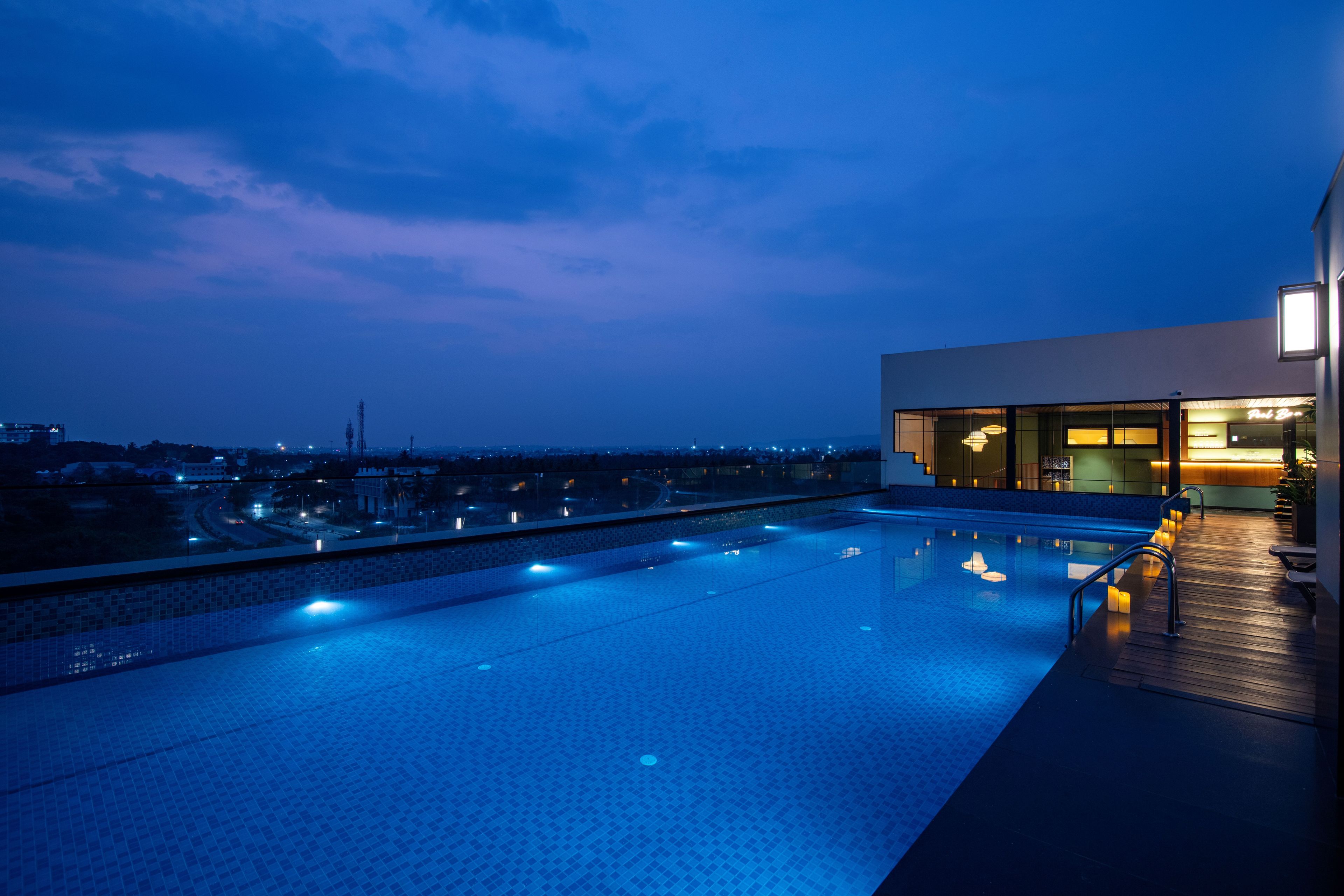 An infinity pool with a view of the cityscape at dusk.