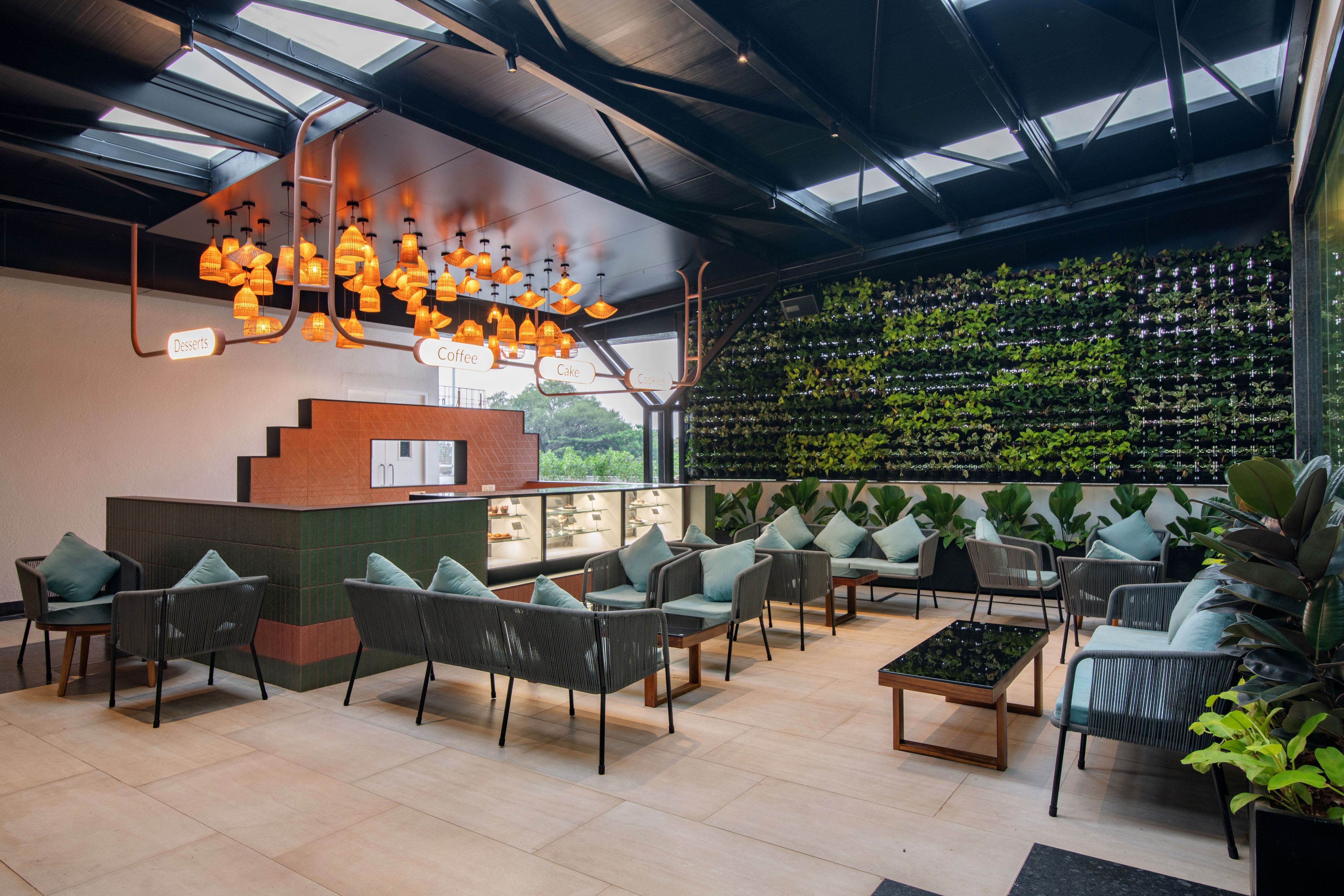 Een modern interieur met een receptiebalie, een zithoek en een wand vol groen.