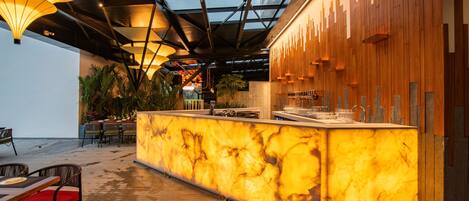 A bar area with a marble counter, wooden paneling, and hanging pendant lights.