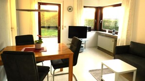 A compact living space with a dining table, chairs, a TV, a sofa, and a small kitchen area. - Apartment 'Schwendemann' with Private Terrace, Balcony and Wi-Fi (Laichingen)