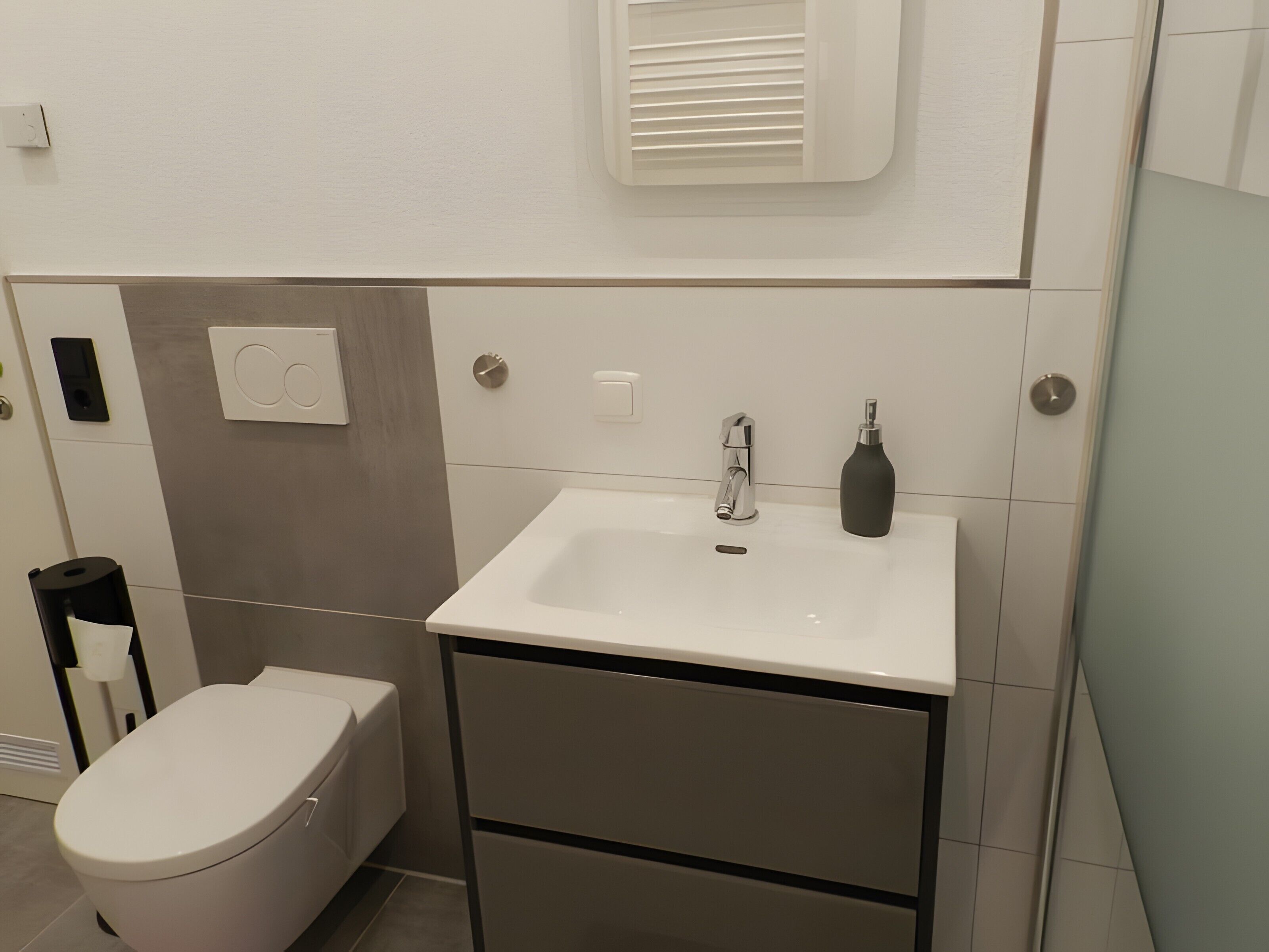 A bathroom with a toilet, a sink, and a mirror.
