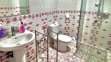 Un baño con piso estampado, un lavamanos, un inodoro y una cabina de ducha de vidrio.