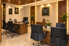 A modern office with a reception desk, black office chairs, and a glass partition. - The Narayanam Hotel (Gwalior)