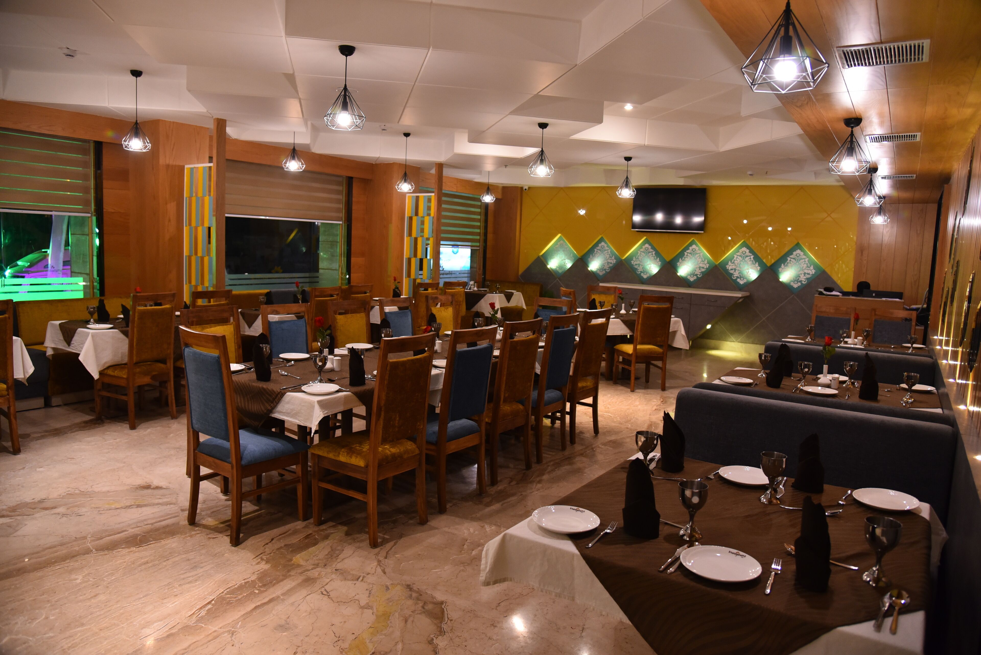 Un restaurant avec des tables et des chaises en bois, une scène et un grand écran.