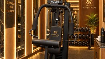Un club de remise en forme situé dans un hôtel, doté d’une salle de sport moderne comprenant divers appareils de musculation et des haltères.