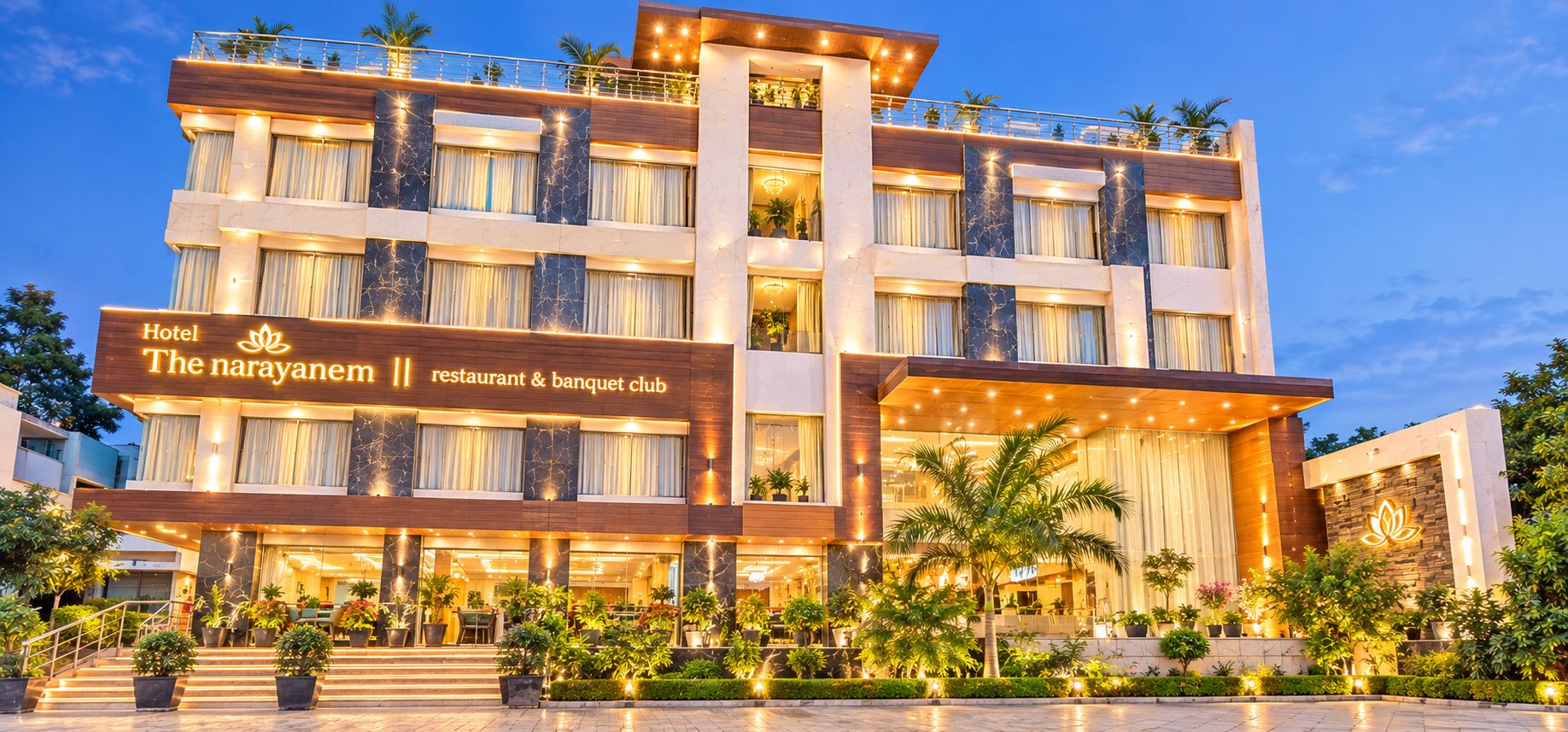 Un hotel de varios pisos con restaurante y salón de banquetes, que presenta una fachada moderna, múltiples balcones y una entrada bien iluminada.