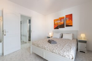 A bedroom with a bed, two bedside tables with lamps, a door, and a shower area. - Vacation 'Casa Vida' with Private Terrace, Balcony and Wi-Fi (Playa Honda)