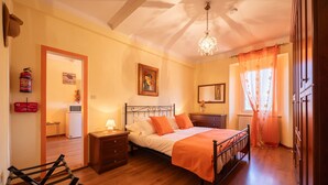 A bedroom with a bed, bedside table, lamp, and a hanging light fixture.