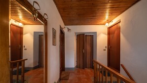 A hallway with wooden doors, a wooden staircase, and a tiled floor.