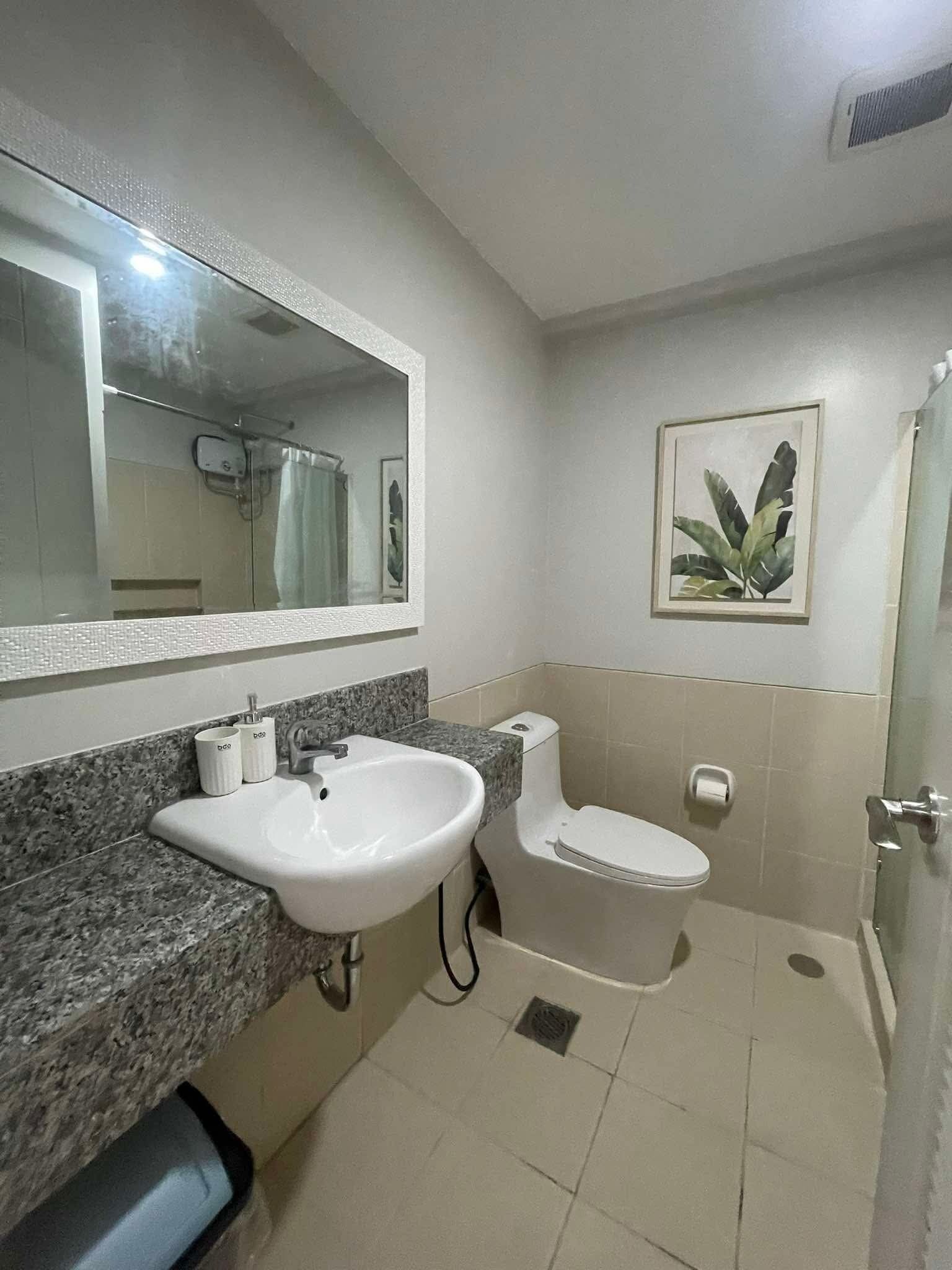 A bathroom with a white sink, a toilet, and a shower.