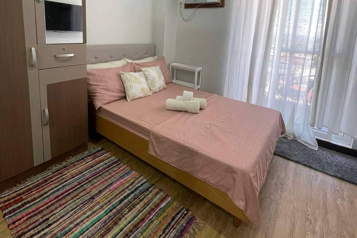 Ein Schlafzimmer mit einem Bett, einem Kleiderschrank, einer Klimaanlage und einem Vorhangfenster.