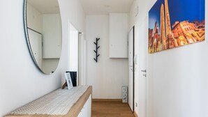 Ein Flur mit einer hölzernen Sitzbank, einem Spiegel, einem gerahmten Bild und einer Wandleuchte.
