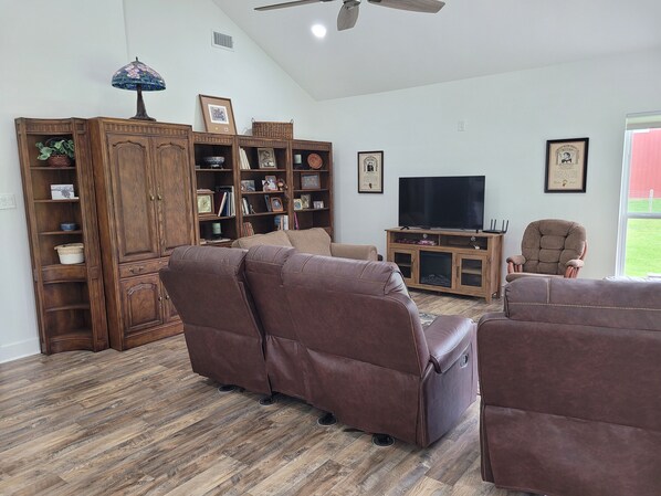 A living room with brown leather sofas, a wooden entertainment unit, and a television. - Country living in new 2bdrm/2bth farmhouse in lovely Chappell Hill with WiFi, AC (Chappell Hill)