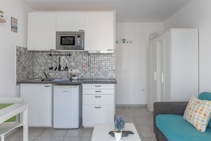 A compact kitchen with a microwave, dishwasher, and patterned backsplash. - Sueño Del Mar Vacation Apartment with Shared Pool, Wi-Fi & Air Conditioning (Puerto del Carmen)