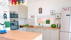 A modern kitchen with white cabinets, stainless steel appliances, a wooden countertop, and a window with a view of the city.