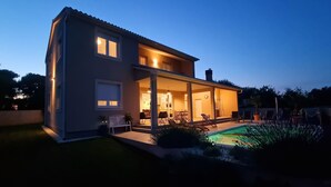 A two-story house with an open patio and a swimming pool.