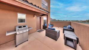 Une terrasse avec un barbecue, des meubles en osier et une porte.