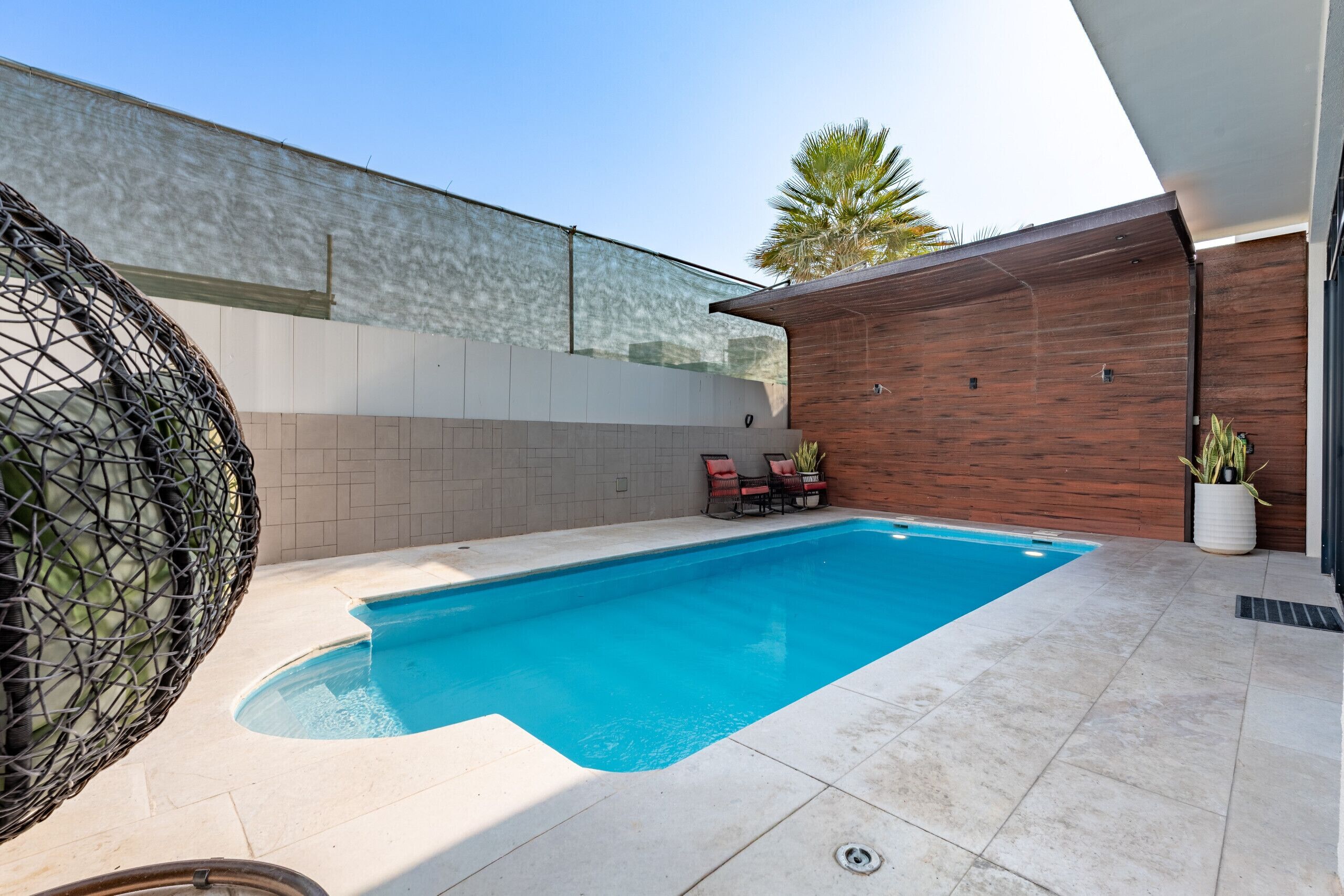 Une piscine à l’eau d’un bleu limpide, entourée d’une terrasse carrelée.