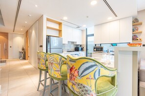 A modern kitchen with white cabinets, a stainless steel refrigerator, and a dining area with colorful chairs. - 4BR Plus Maids Villa with Dedicated Outdoor Pool, Near Clubhouse by Deluxe Holiday Homes (Dubai)