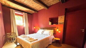 Un dormitorio acogedor con techo de madera, una cama con colcha estampada, una mesita pequeña y una silla.