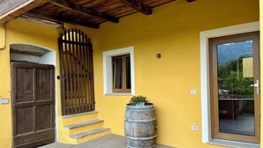 Un edificio amarillo con una puerta de madera, una ventana y un barril.