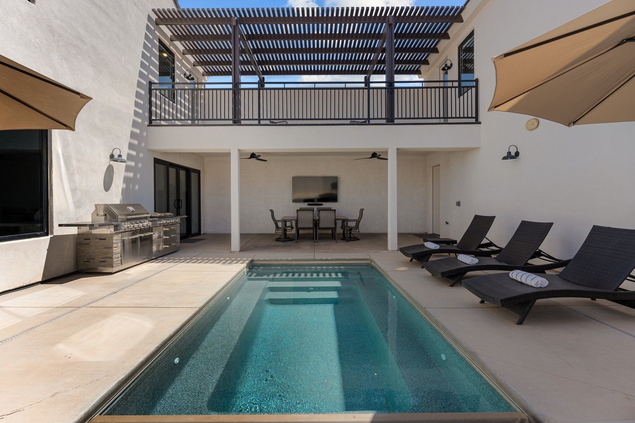 An outdoor pool area with lounge chairs, a barbecue grill, and a dining set.