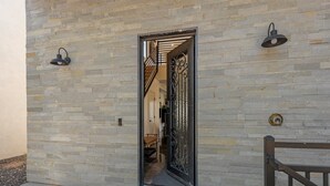 A stone wall entrance with a metal gate, a staircase, and two wall-mounted lights. - Desert Jewel With Private Gym And Pool 4 Bedroom Townhouse (Hurricane)