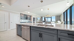 A modern kitchen with a large island, built-in appliances, and a view to the outside.