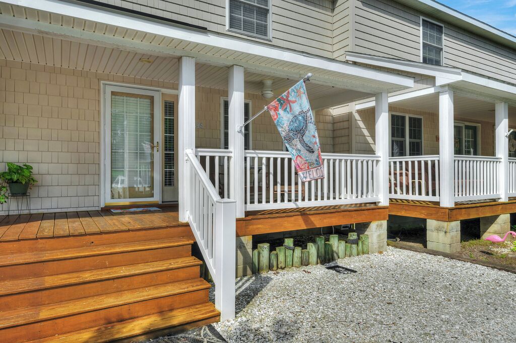 A two-story house with a covered porch, wooden steps, and a flag.