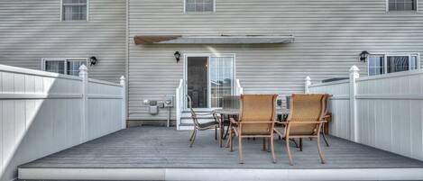 Una casa de dos pisos con un patio techado que incluye una mesa y sillas.