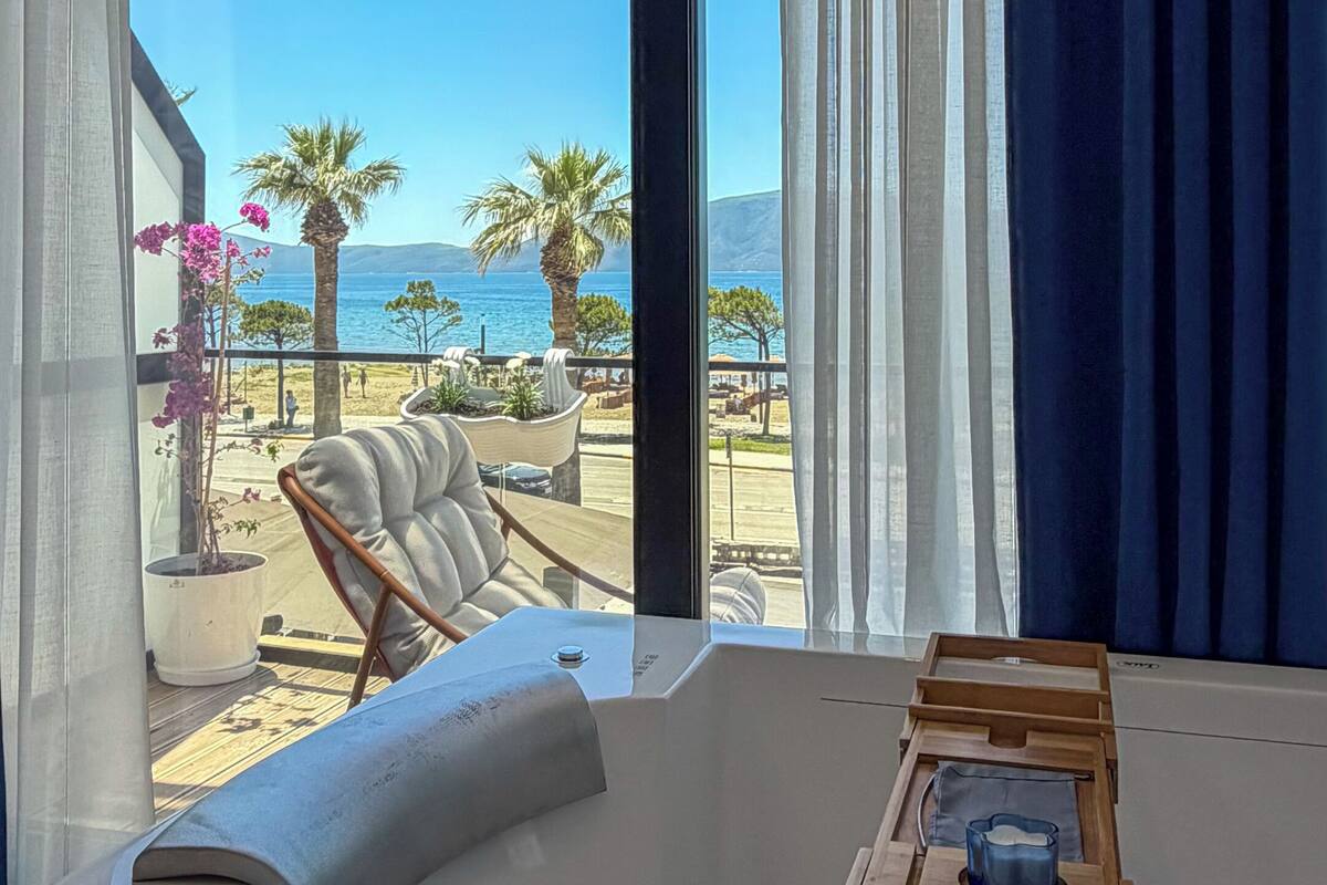 Una habitación con un ventanal grande, una bañera y una bandeja de madera con una vela.
