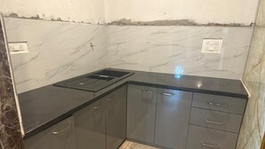 A kitchen with marble countertops, dark cabinets, and a built-in sink. - Aishwarya Homestay (Gokarna)