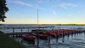A calm lake with a wooden dock and several red boats docked. - Cozy half of the house near the lake with barbecue, within walking distance of the bathing area & Satama (Wendisch Rietz)