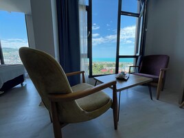 Una habitación con un ventanal grande, una cama, una mesa con un plato de comida y dos sillas.