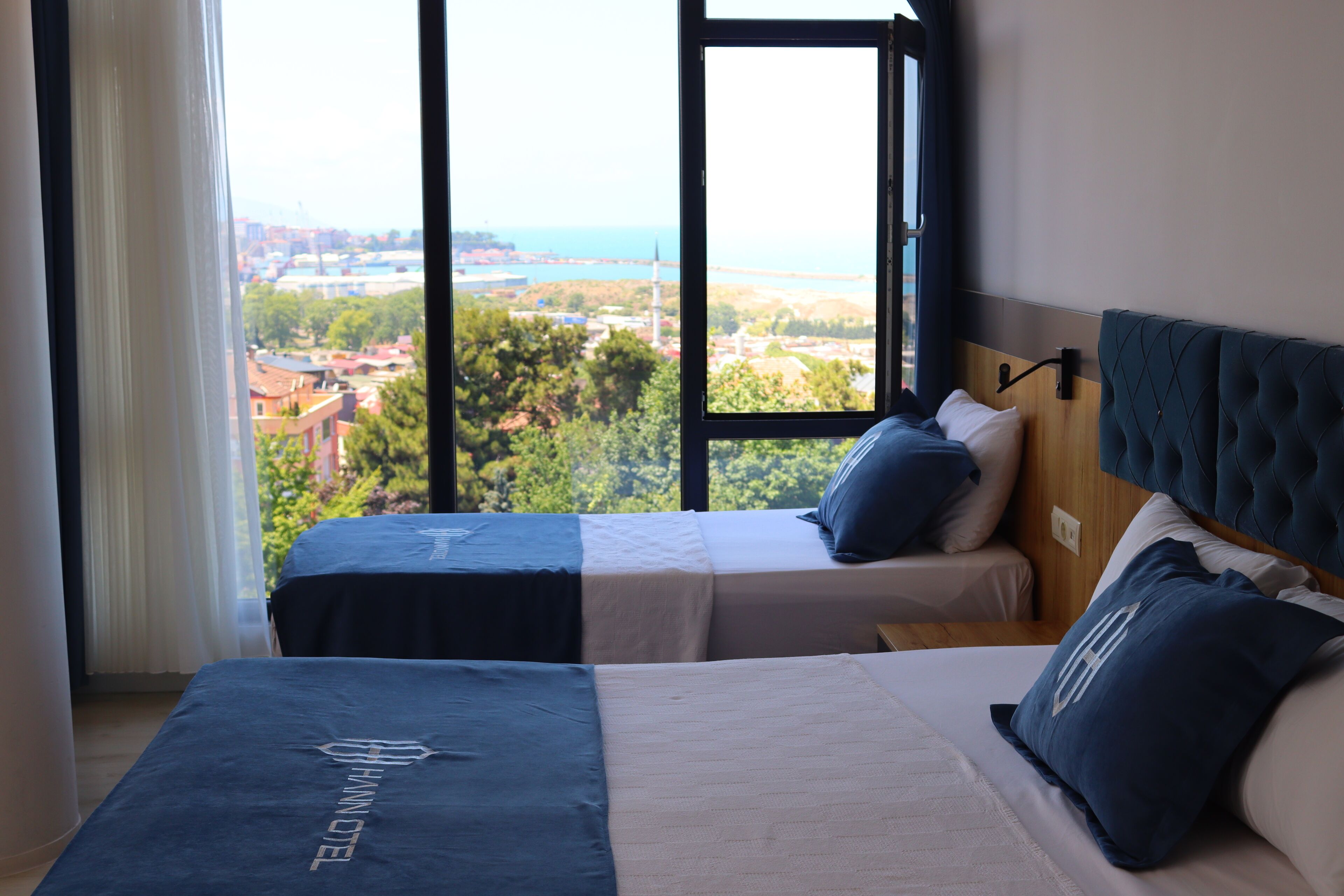 Ein Hotelzimmer mit zwei Betten und Blick auf die Stadt, mit einem großen Fenster.