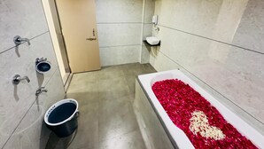 Un bagno moderno con una vasca da bagno piena di petali di rosa, un water e un lavandino.