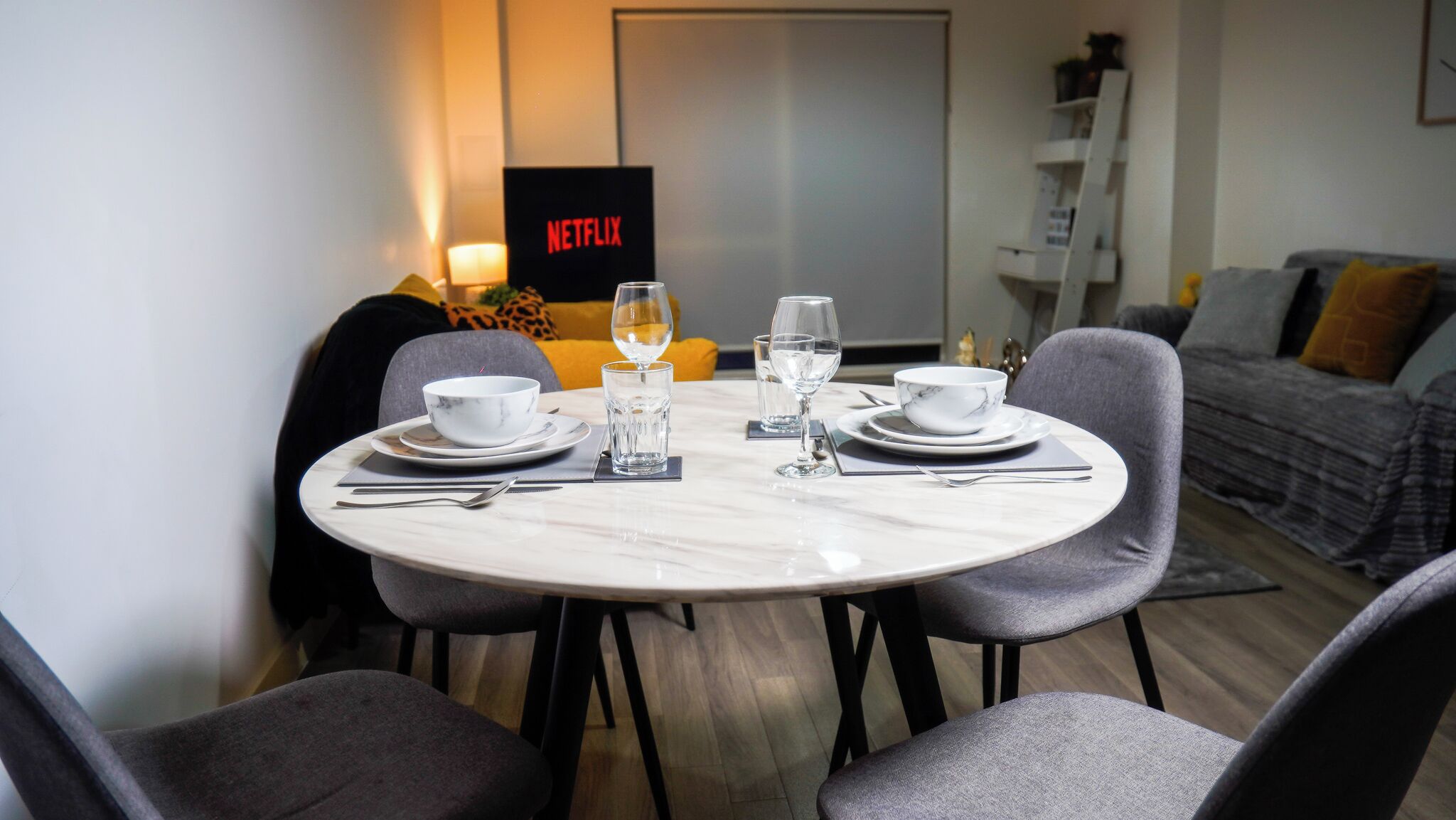 A dining area with a round table set for four, including bowls, glasses, and cutlery.