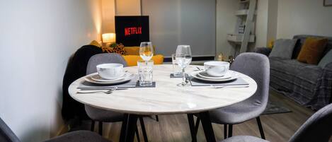 A dining area with a round table set for four, including bowls, glasses, and cutlery.