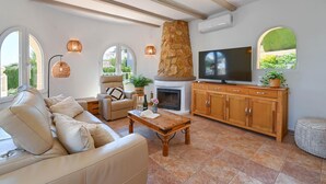 A living room with a stone fireplace, a television, and a sofa. - Cala Serena - Benitachell, Costa Blanca (Benitachell)