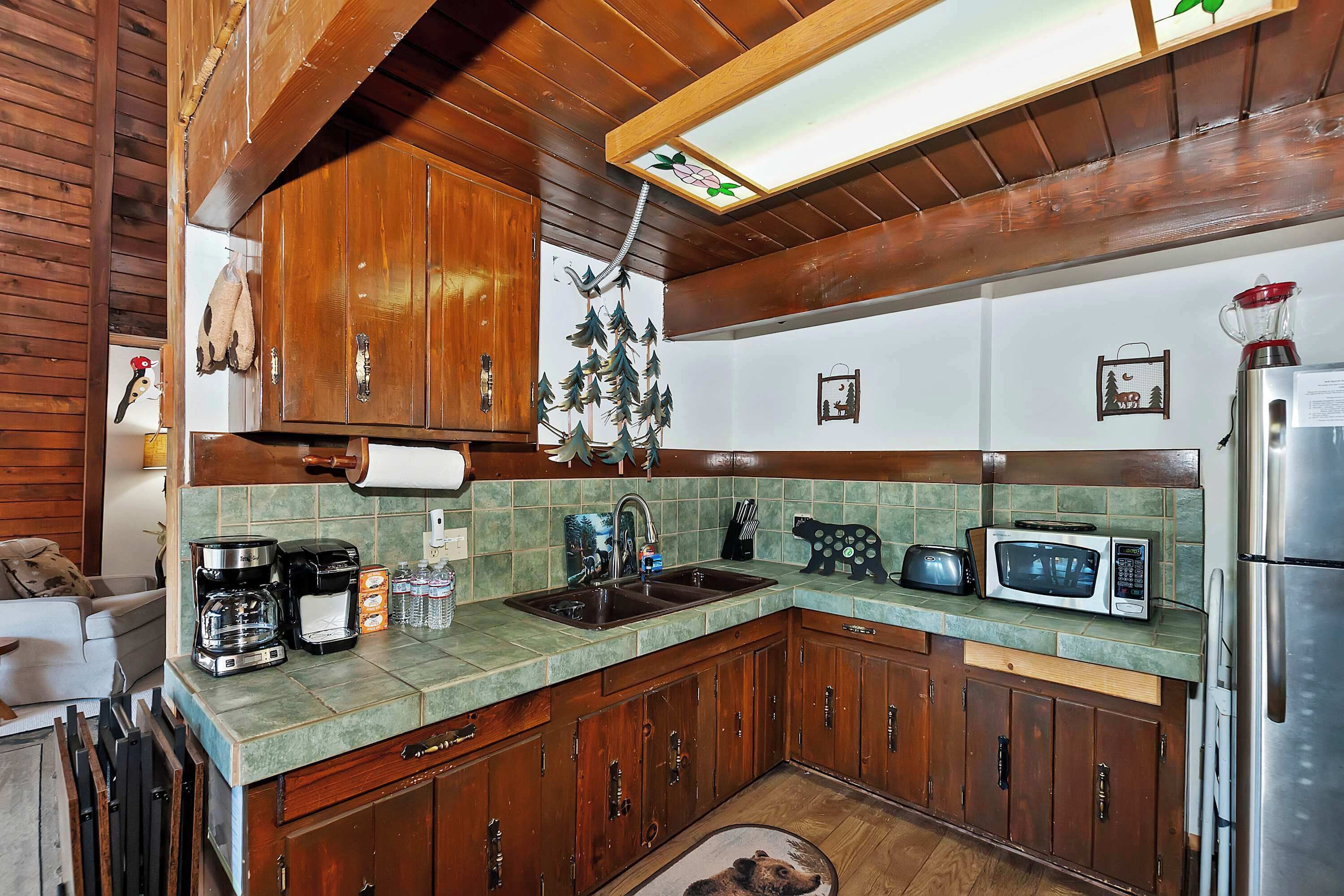 A kitchen with wooden cabinets, a microwave, a coffee maker, and a sink.