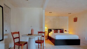 Un dormitori amb llit, taula de nit, làmpada i dues cadires.