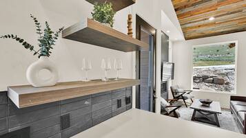 Una cocina moderna con estante de madera, planta en maceta y copas de vino.