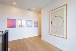 A modern interior with a wooden floor, white walls, and a staircase.