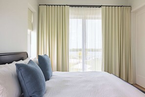 A hotel room with a large bed, white bedding, and blue pillows. - The Dreamside House at Lunara Bay (Key West)