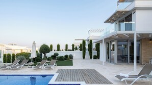 A modern outdoor pool area with lounge chairs and a wooden deck. - Villa with Private pool (Protaras)