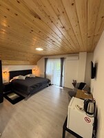 Un dormitorio con techo de madera, una cama, un escritorio y un televisor.