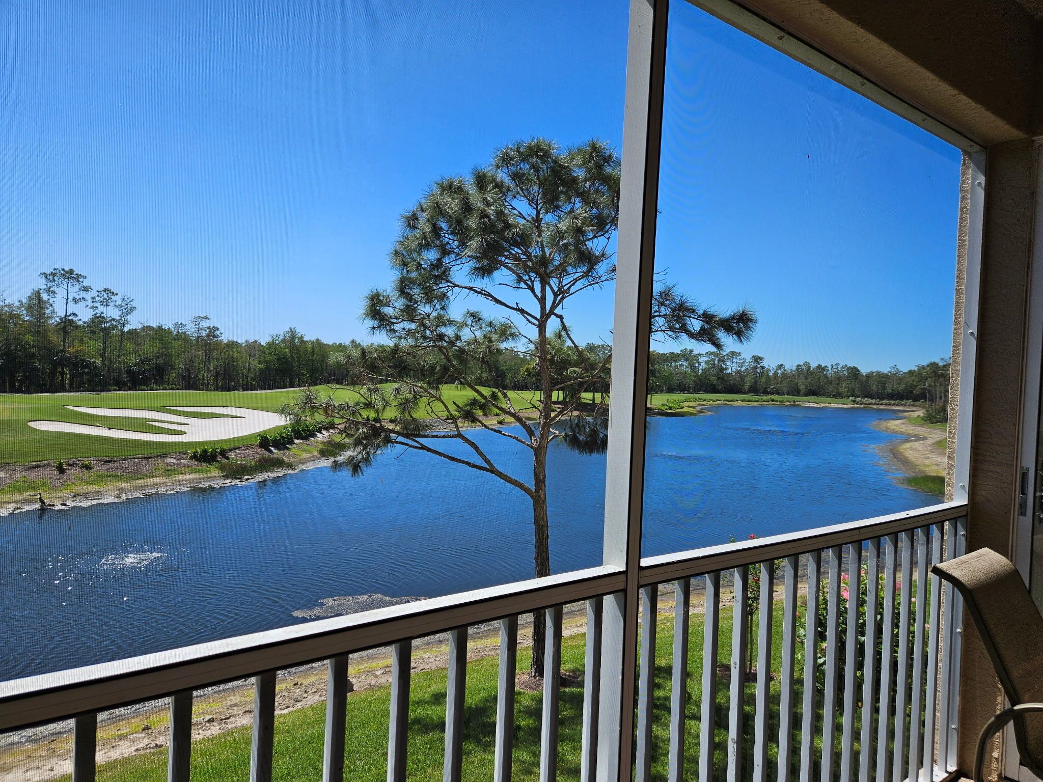 Vista desde un balcón sobre un campo de golf y un lago.